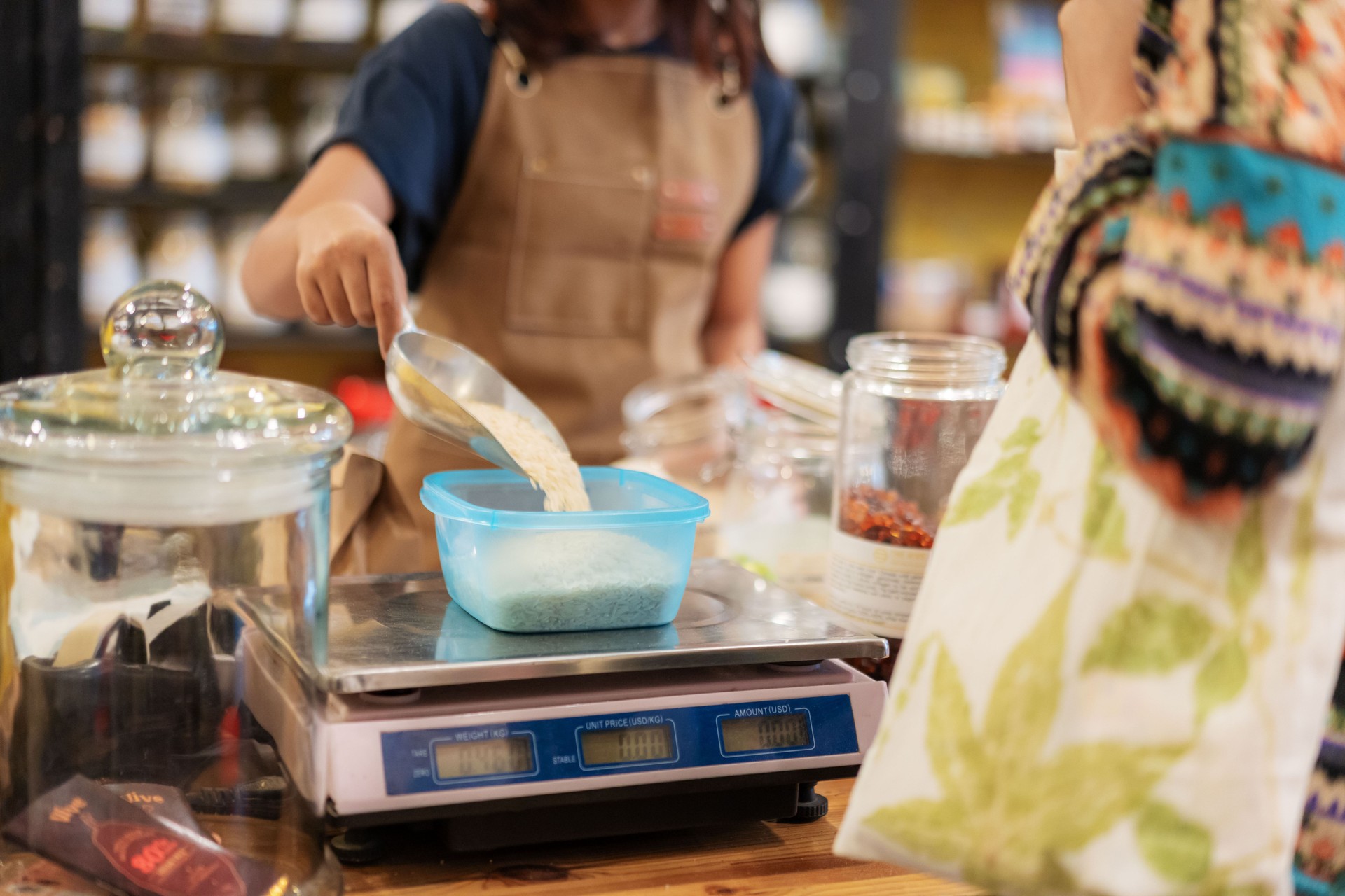 Close Up Store Clerk Weighting Dried Goods with Reusable Container at zero waste store